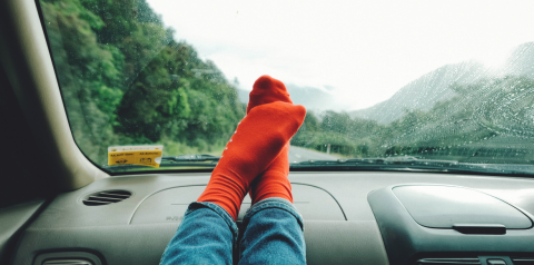 Person in socks with feet on car dashboard