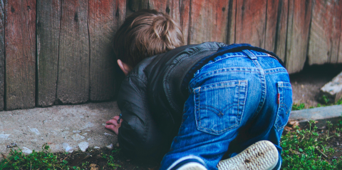 Child peeking through a fence.